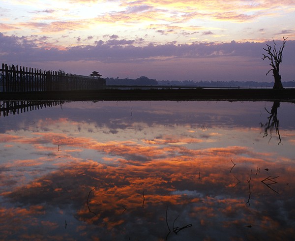 Tagesanbruch an der alten U Bein-Brücke nahe Amarapura. Seitdem der Taungthaman-See aufgestaut ist, spiegeln sich die Wolken in ihm das ganze Jahr über.