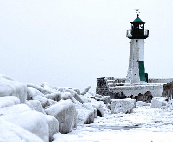 Der Leuchtturm von Sassnitz während eines strengen Winters. Die Wellenbrecher tragen dicke Eispanzer.